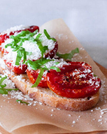 Roasted tomatoes on toast with parmesan and basil.